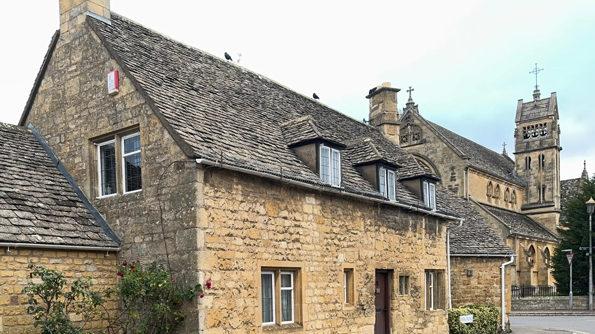 Weathered Cotswold stone slate roof with stone dormers on a traditional honey-stone cottage